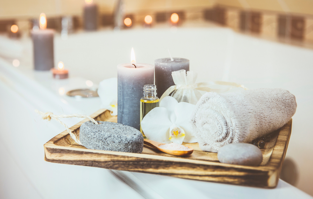 towels and candles in a tray on a tub.